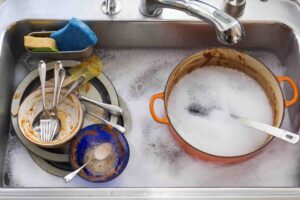 Dishes and Pans soaked in soup, one of the best kitchen cleaning hacks to break down touch food residue. 