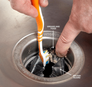 A person using a toothbrush to reach a small space in the sink