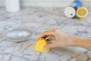 A person cleaning the kitchen countertop with a lemon